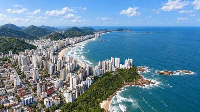 Orla da Praia das Astúrias vista do alto, com os prédios, a areia e o mar (imagem ilustrativa)