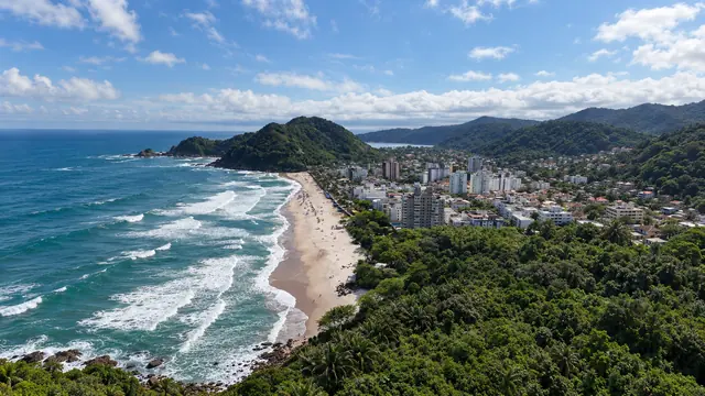 Praia do Tombo vista do alto do morro, com a mata em primeiro plano e os prédios do bairro (imagem ilustrativa)